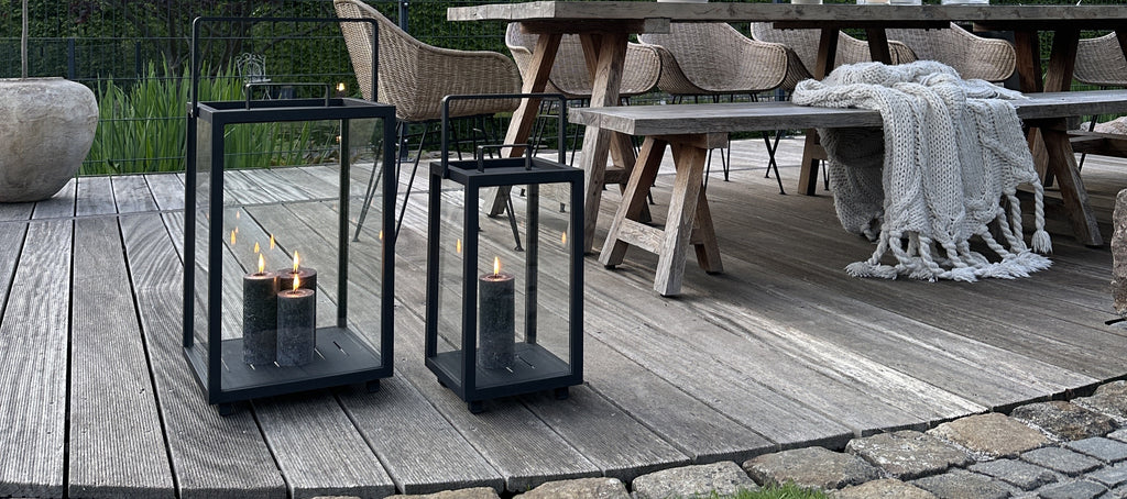 Two black lanterns with grey candle lights in the garden