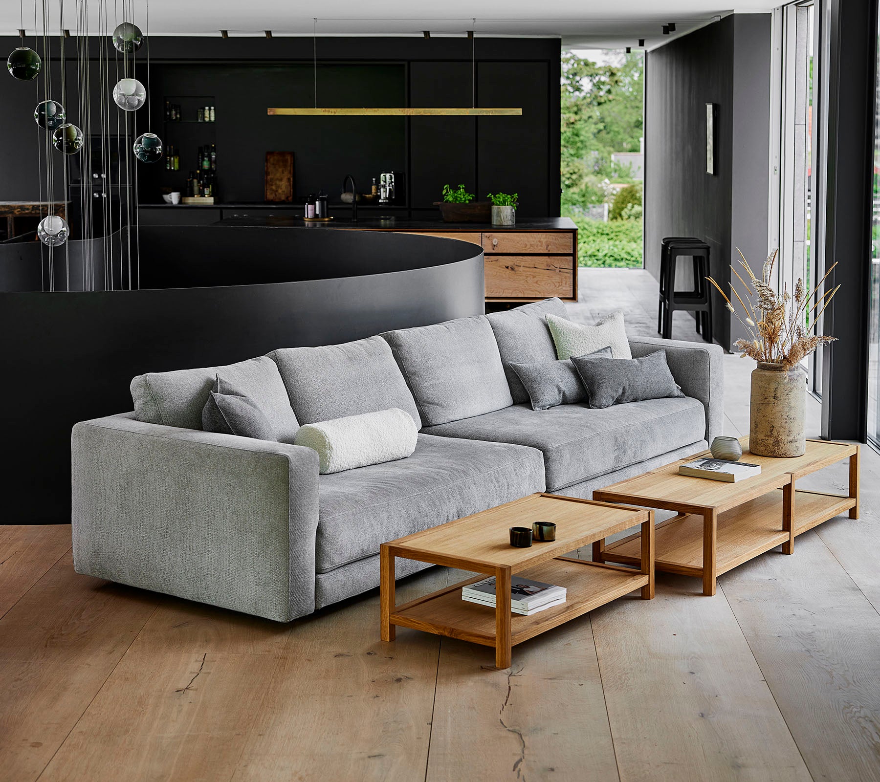 En modern, grå soffa med mjuka kuddar bredvid träkaffebord i en nutida miljö med stilren inredning.