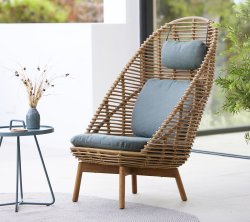 Stilig vävd stol med hög rygg, vadderad sits och matchande kudde, tillsammans med ett litet bord och en dekorativ vas.