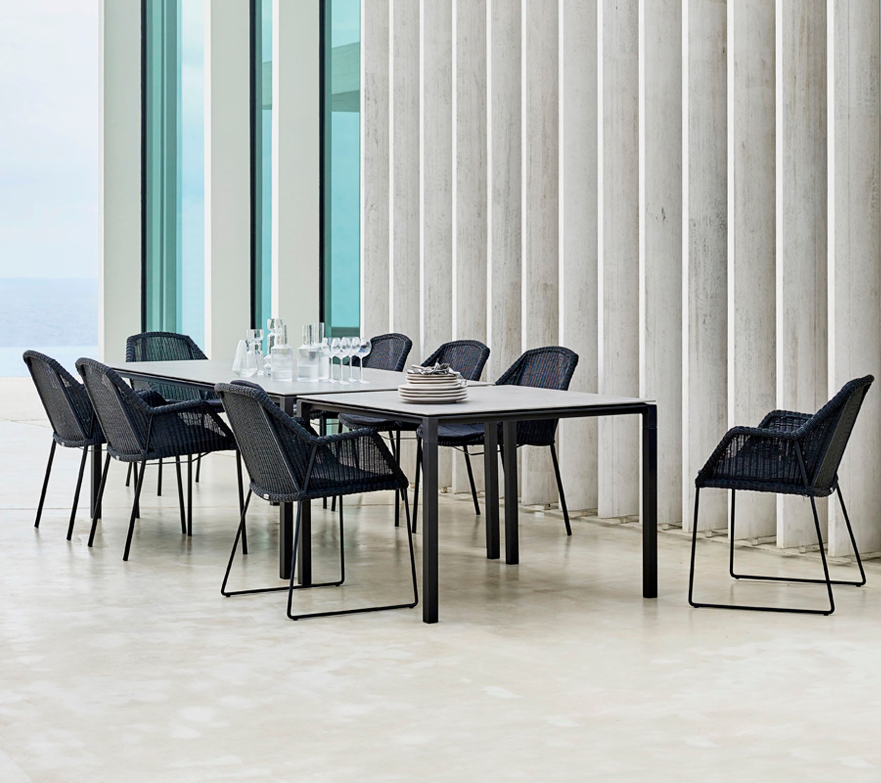 Ett modernt matbordset med svarta stolar runt om, med minimalistiska designelement och en elegant dukning.