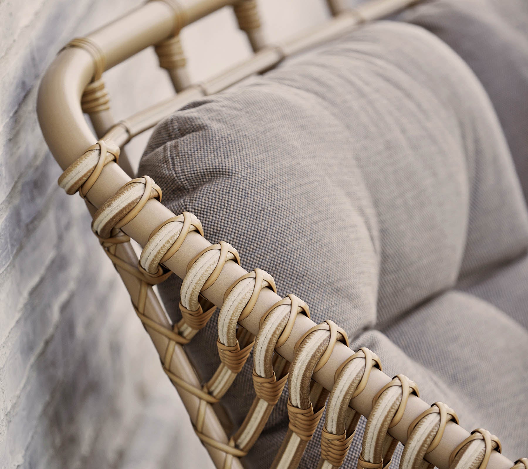 Stiligt sittalternativ med en beige vävd ram och mjuka grå kuddar, perfekt för att förbättra modern inredning.