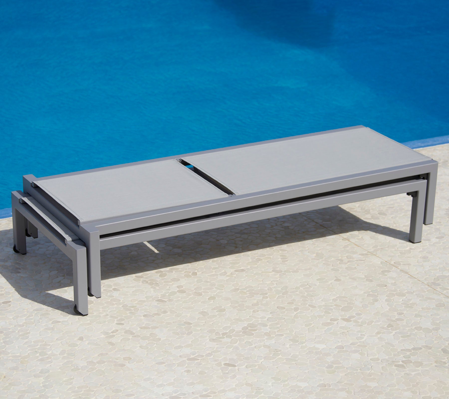 Stilfullt grå loungesäng bredvid en pool, med en snygg design och praktisk funktionalitet för avkoppling.