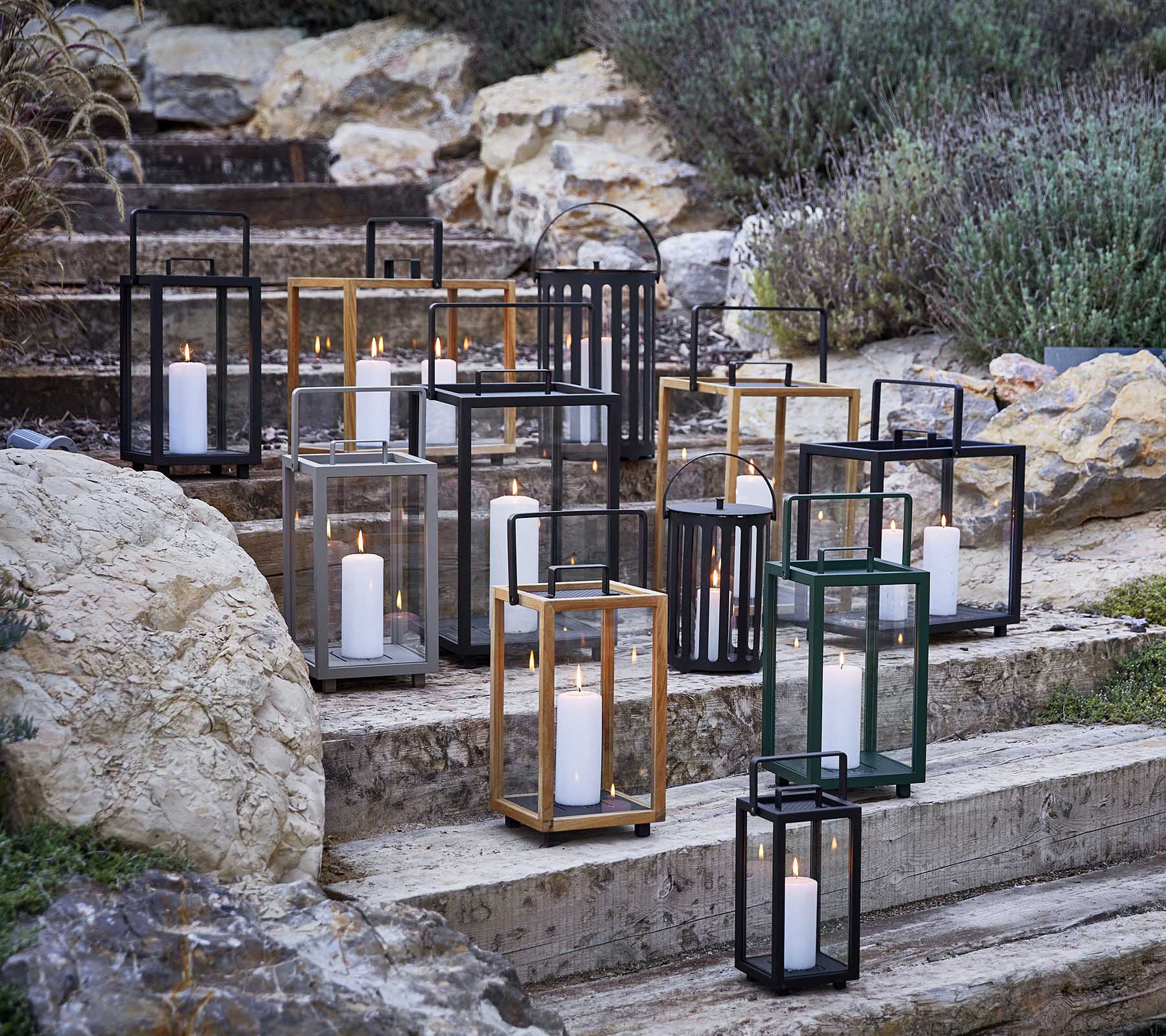 Samling av dekorativa lykter i olika stilar och färger, med mjukt stearinljus, konstnärligt arrangerade på stentrappor.