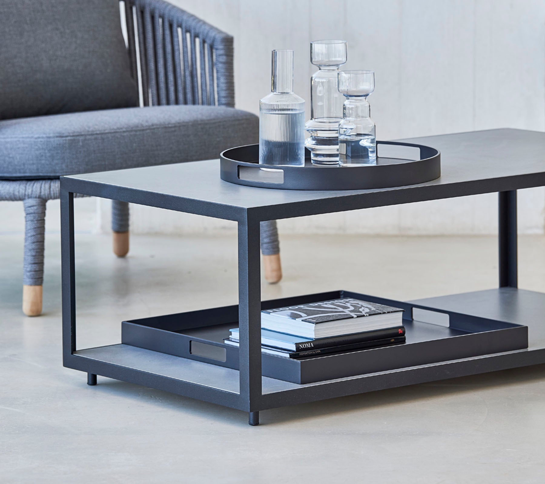 Modernt soffbord med en sleek design, med en bricka, glas och böcker på den nedre hyllan. Perfekt för stiliga vardagsrum.