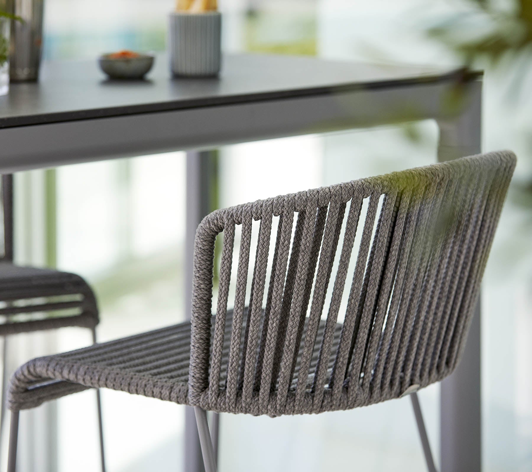 Stilig grå stol med en slimmad design, med vertikala ränder och en modern estetik, placerad bredvid ett minimalistiskt bord.