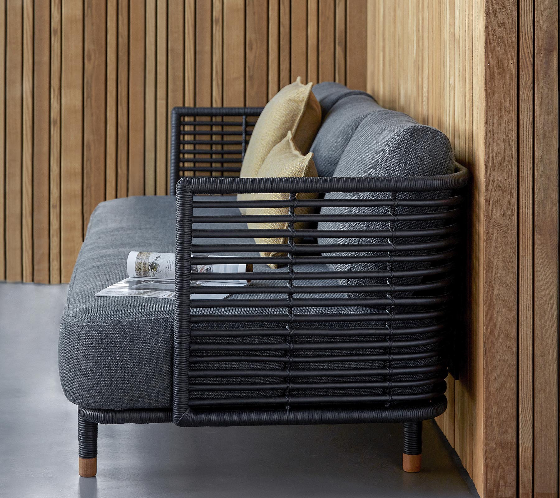 Stiligt soffbord med en slank design i texturerad grått tyg och dekorativa kuddar, kompletterat av en modern slattedram.