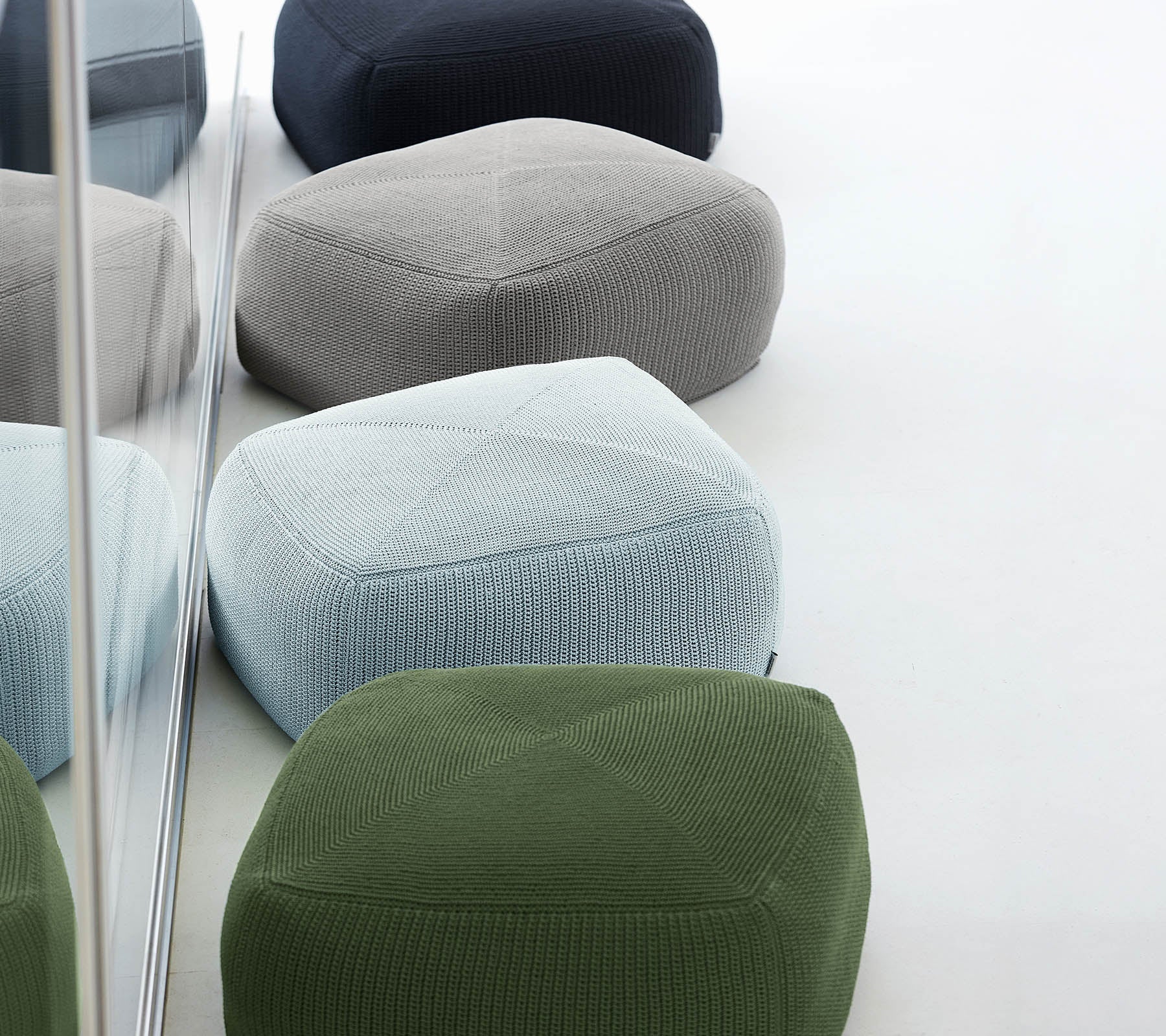 En samling av färgglada, texturerade poufer i olika nyanser, arrangerade tillsammans, som återspeglar stilig och modern design.