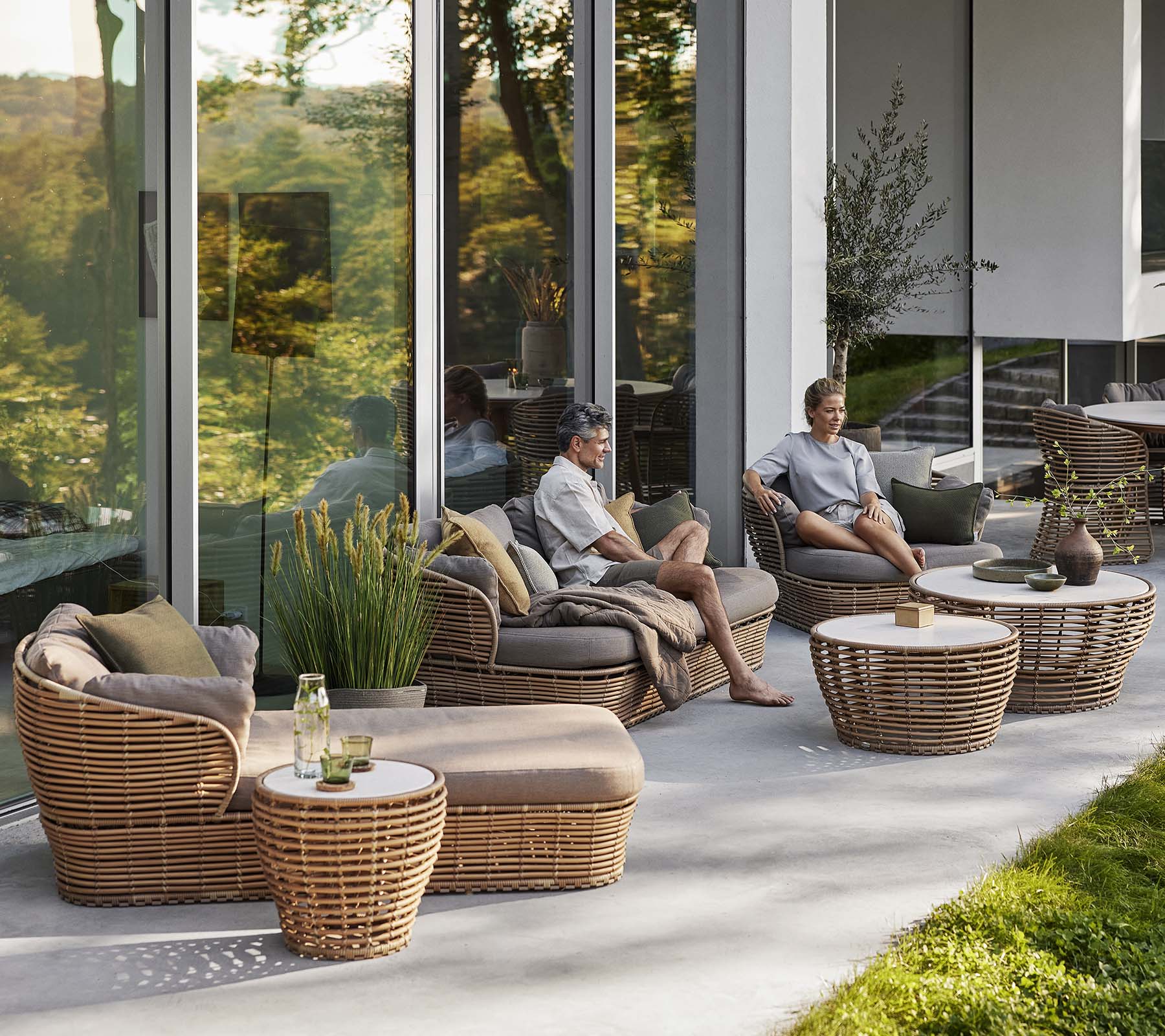 Stilfullt sittområde med en korgsolsäng, loungestol och soffbord med naturliga element, vilket skapar en mysig, avslappnande atmosfär.