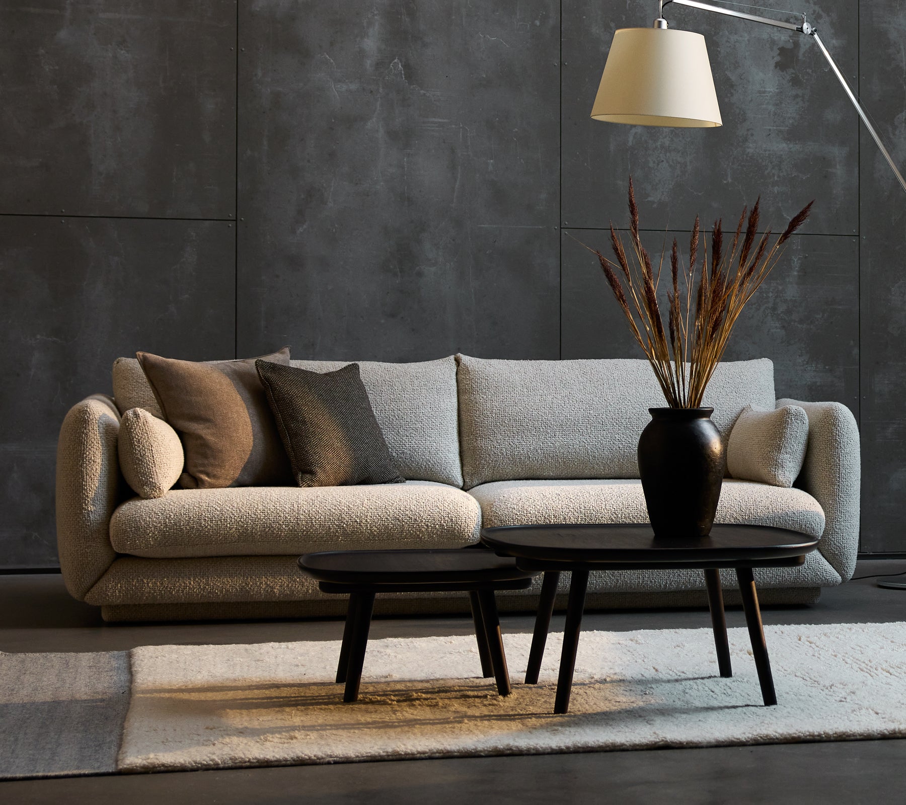 Bloom 3-sits soffa i sandfärg med dekorativa kuddar, tillsammans med två Pace soffbord i olika storlekar och en stilren golvlampa.