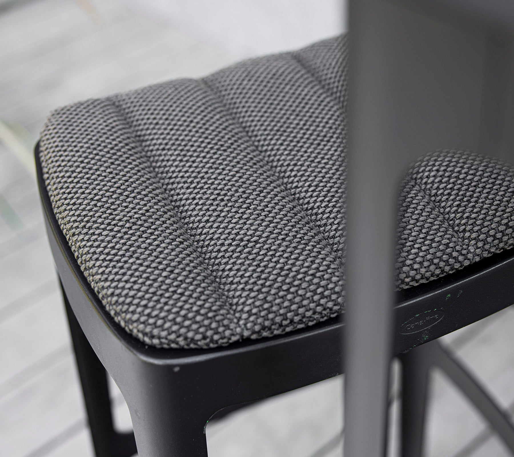 Närbild av en texturerad svart stolssits med en kviltad design som visar modern hantverk och uppmärksamhet på detaljer.