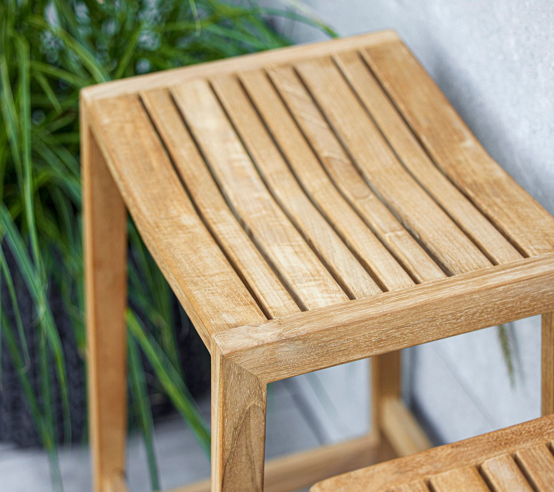 Ett smidigt träsidebord med design av lameller på toppen, med en ljus finish som komplementerar den omgivande grönskan.