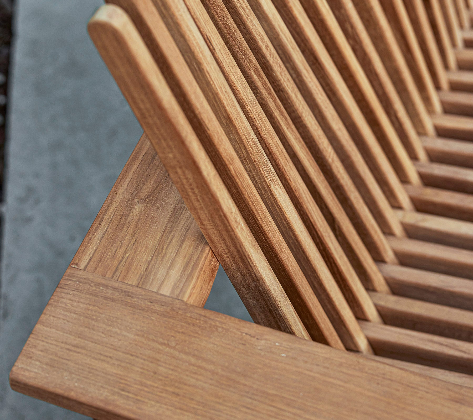 Närbild av ett trämöbel med lamelldesign som visar den naturliga ådringen och hantverksdetaljer.