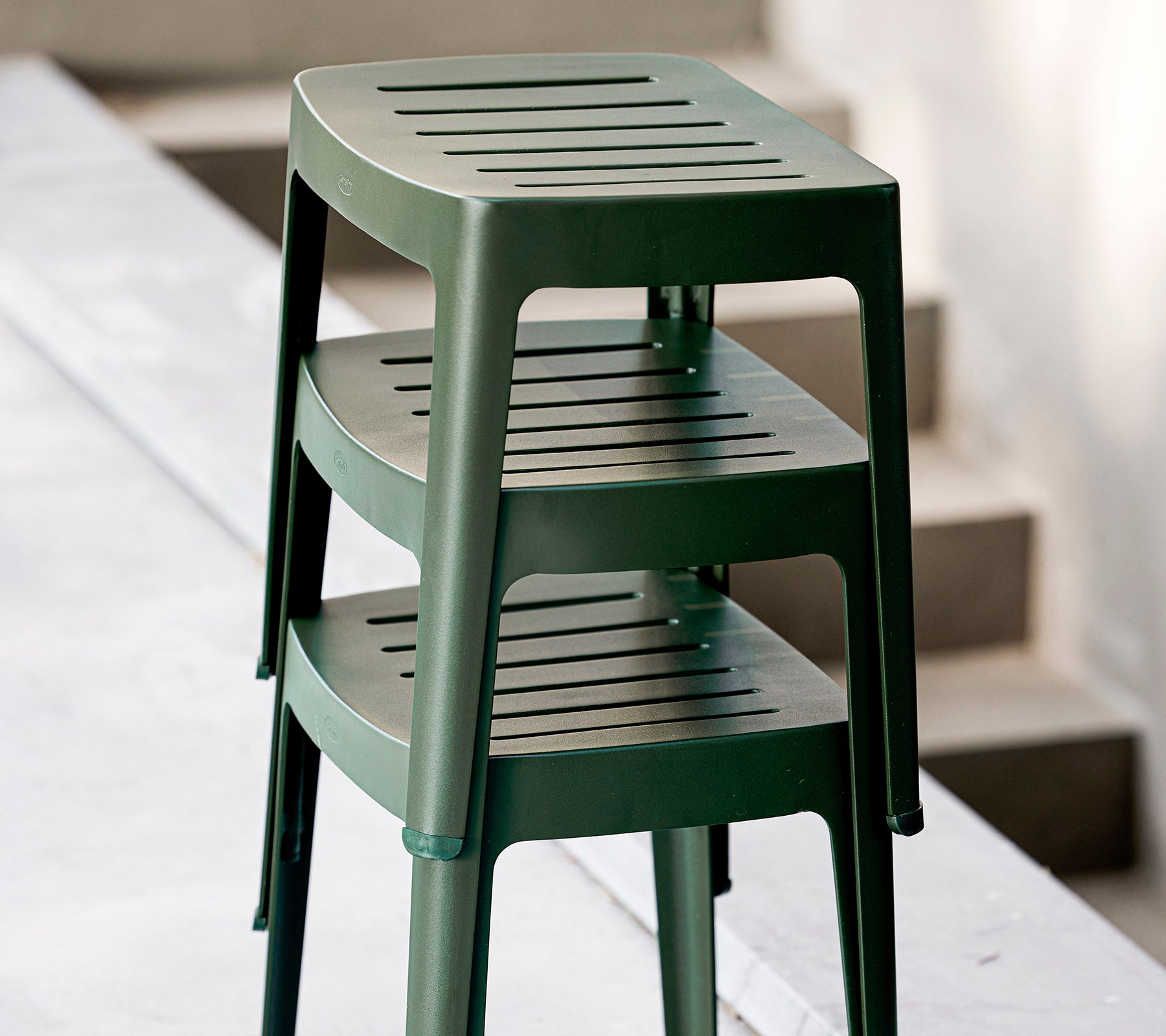 Staplade gröna plaststolar med sprötsitsar, designade för avslappnad användning. Idealiska för mångsidiga sittarrangemang.