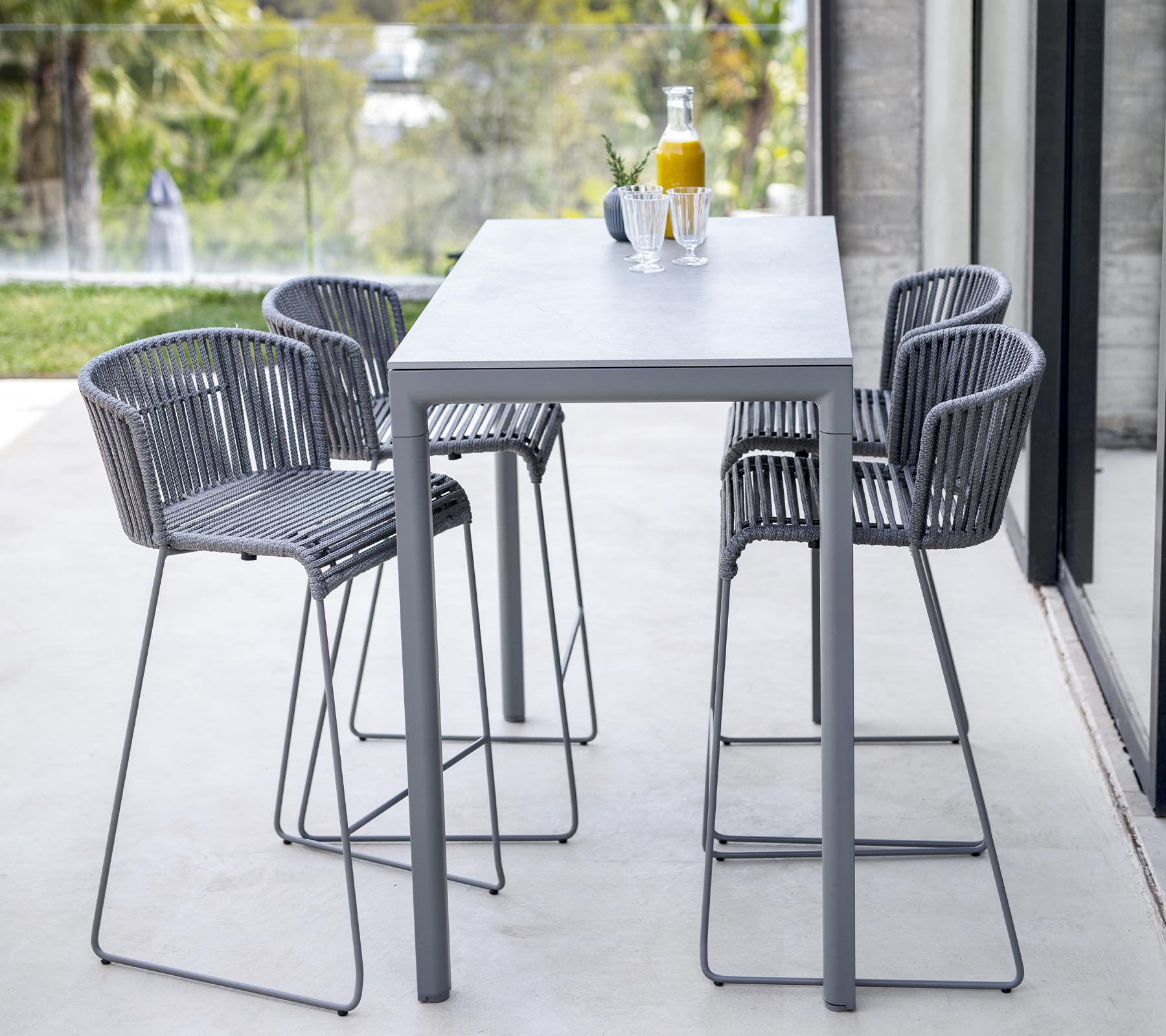 Moderna matgrupp med ett stilrent bord och fyra högryggade stolar med minimalistisk design, perfekt för informella sammankomster.