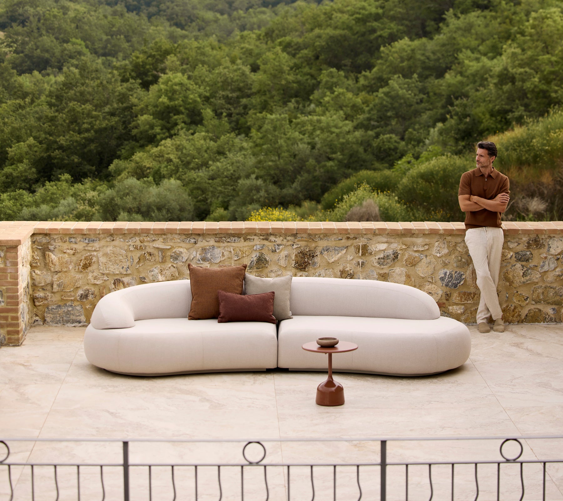 Mellow lounge-soffa med Rise-kuddar och ett Glaze soffbord, placerad mot en frodig grön bakgrund.