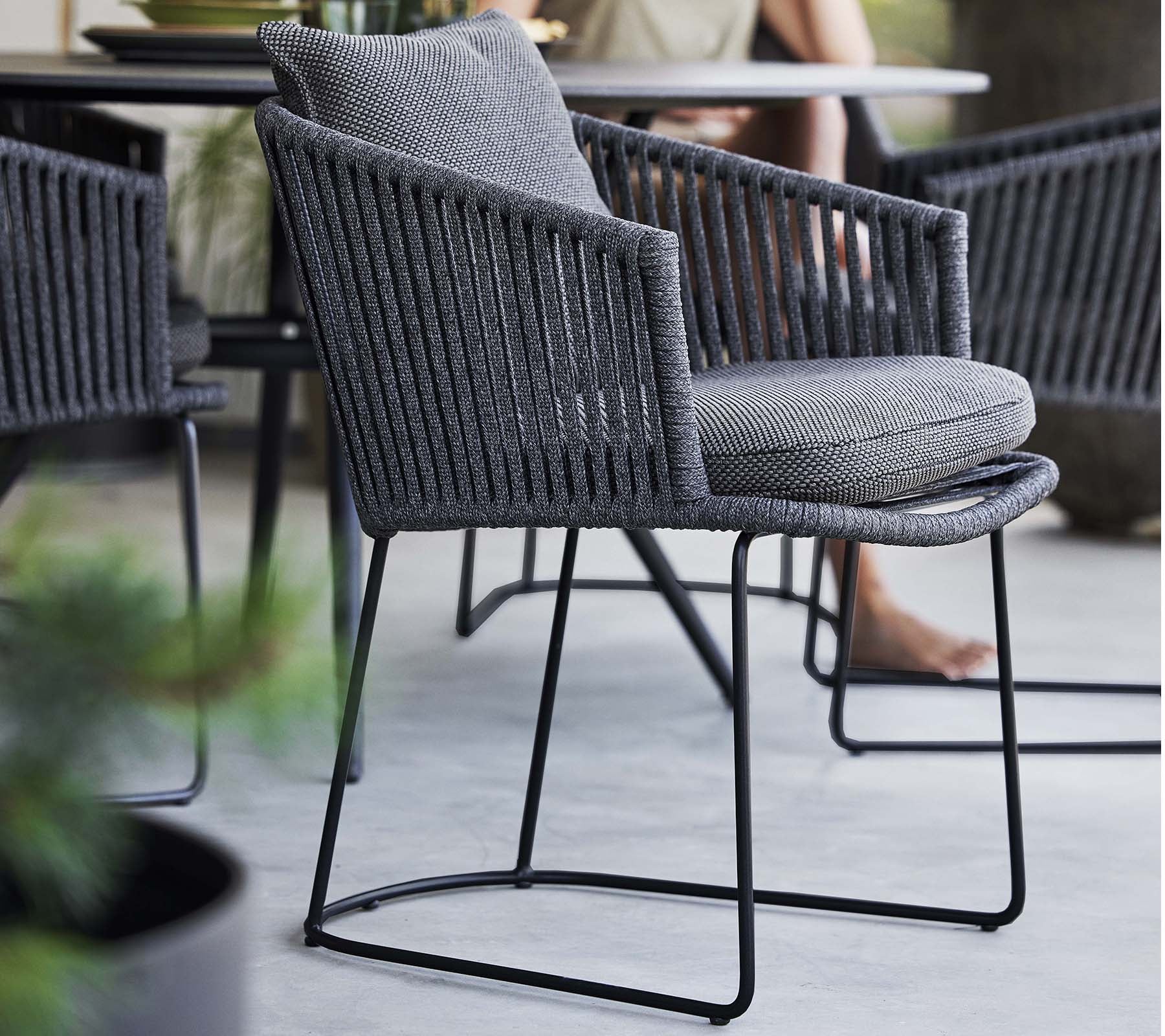 Stilig stol med vävt mönster och mjukt kudde, stödd av en slank metallram, perfekt för moderna utrymmen.