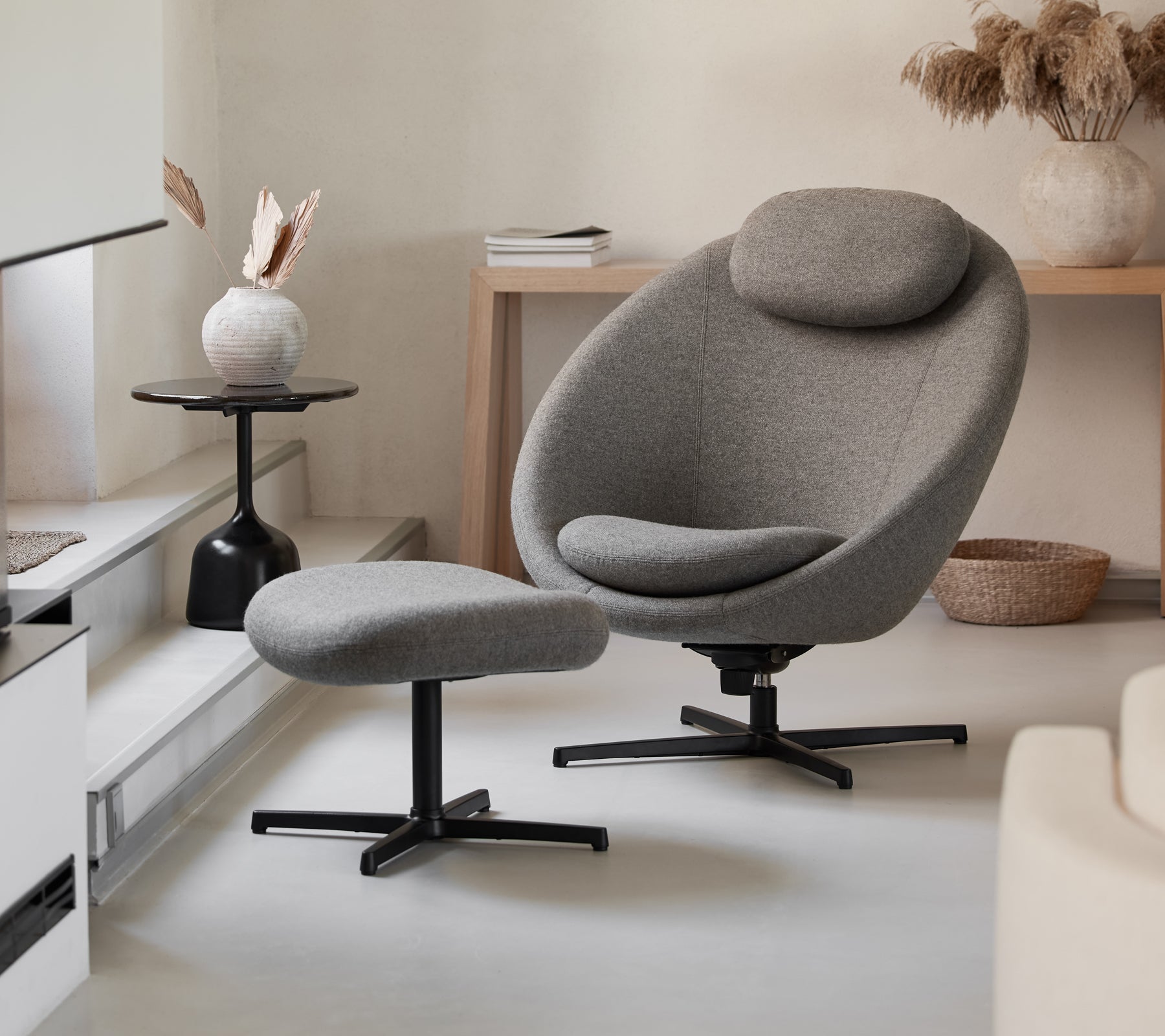 Stilfull grå stol med matchande fotpall, med en slank design och bekväma kurvor, kompletterat av moderna dekorelement.