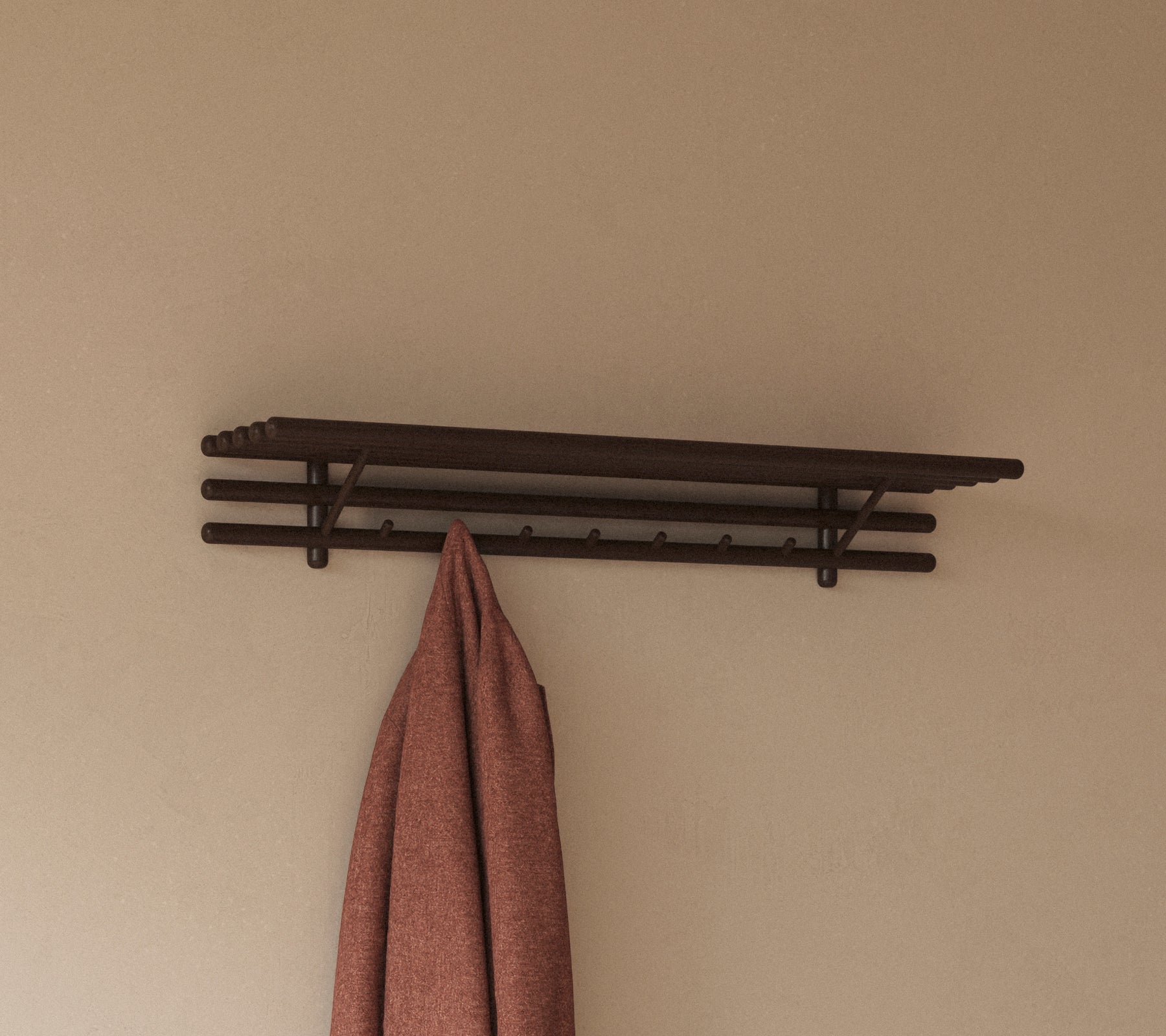 En minimalistisk hylla med flera krokar som håller en hängande trasa, designad för praktisk förvaring och organisering.