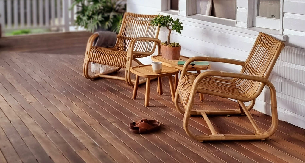 Two Curve lounge chairs on a veranda with teak side tables