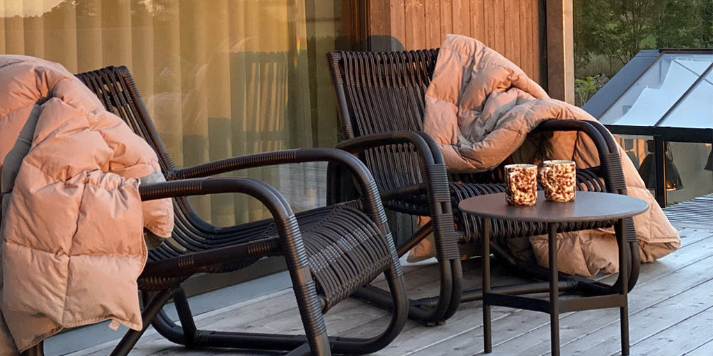 Two Curve lounge chairs in black with blankets and Twist side table with coffee cups