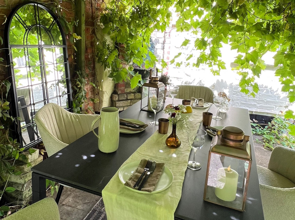 Pergola with grapevines above ceiling, bouclé design outdoor chairs, black ceramic outdoor garden table