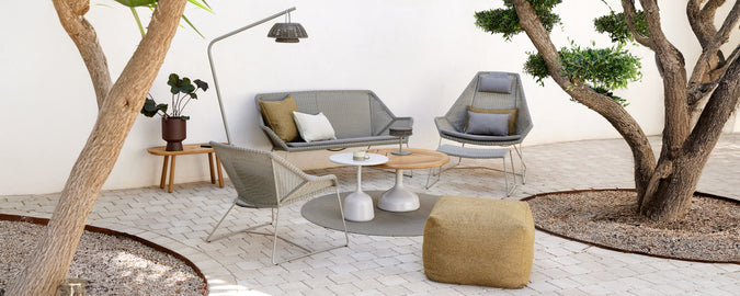 Modern loungeinredning med en grå soffa, grå stol, träkaffebord och en gul puff.