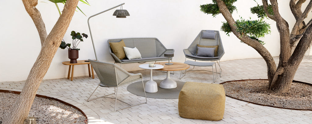 Modern loungeinredning med en grå soffa, grå stol, träkaffebord och en gul puff.