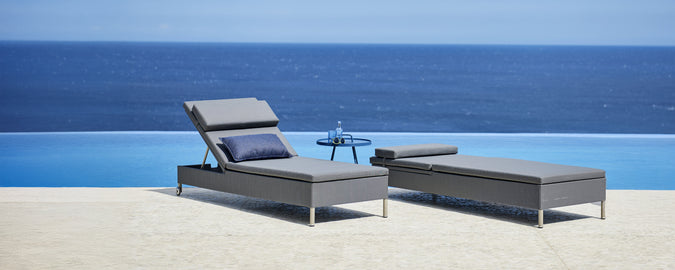 Grå lounge stol och chaiselong vid en pool med utsikt över havet.