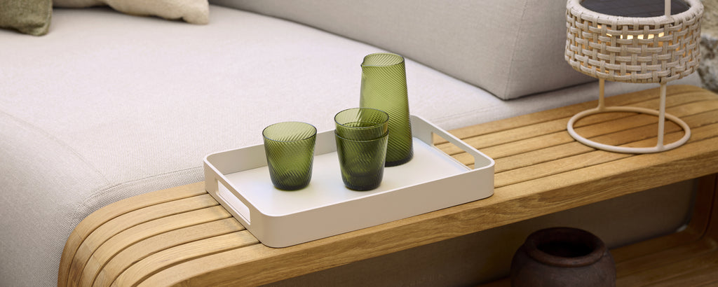Modern loungeinredning med grönt glas på en vit bricka.