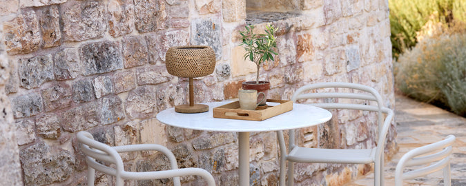 Modern utomhusmiljö med vitt bord, vita stolar och bruna dekorationselement.