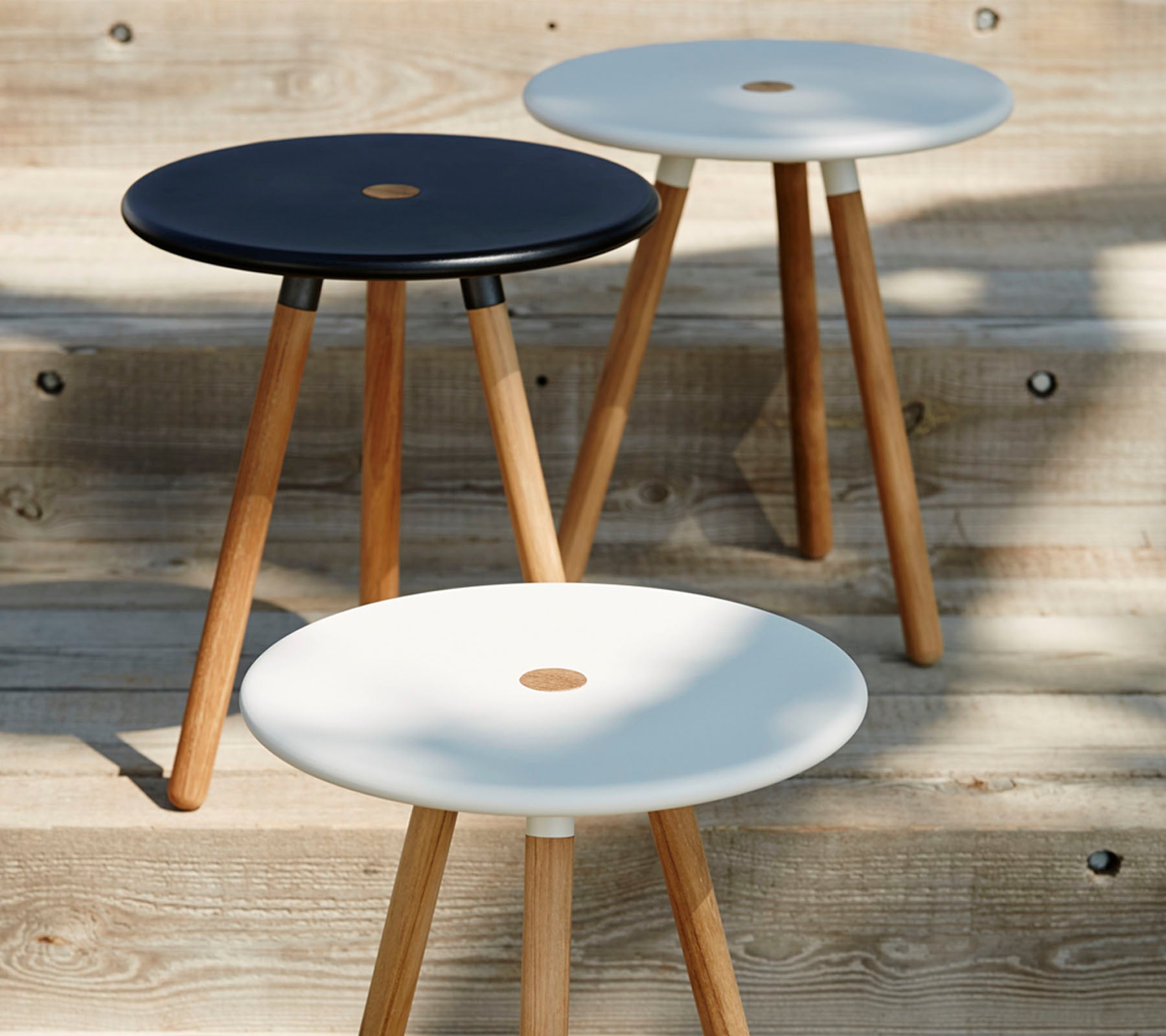 Tre minimalistiska pallar med runda svart och vita toppar, var och en stödd av träben, som visar upp en modern och stilren design.