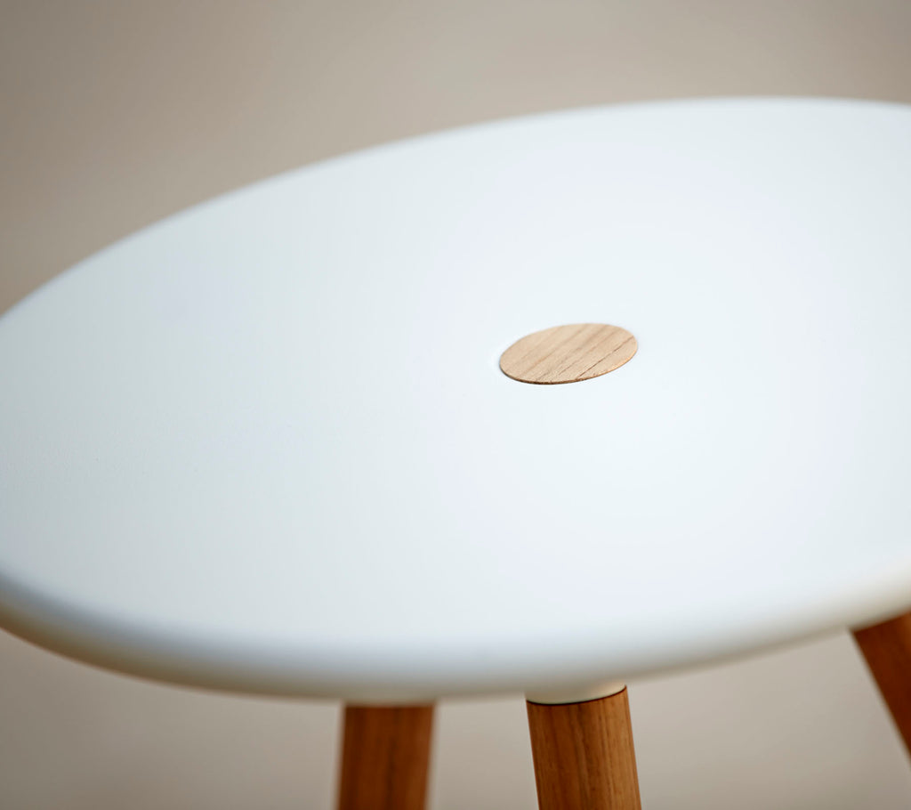 En stilig pall med en slät vit topp som har en liten trädetalj, stödd av träben. Ideal för modern inredning.