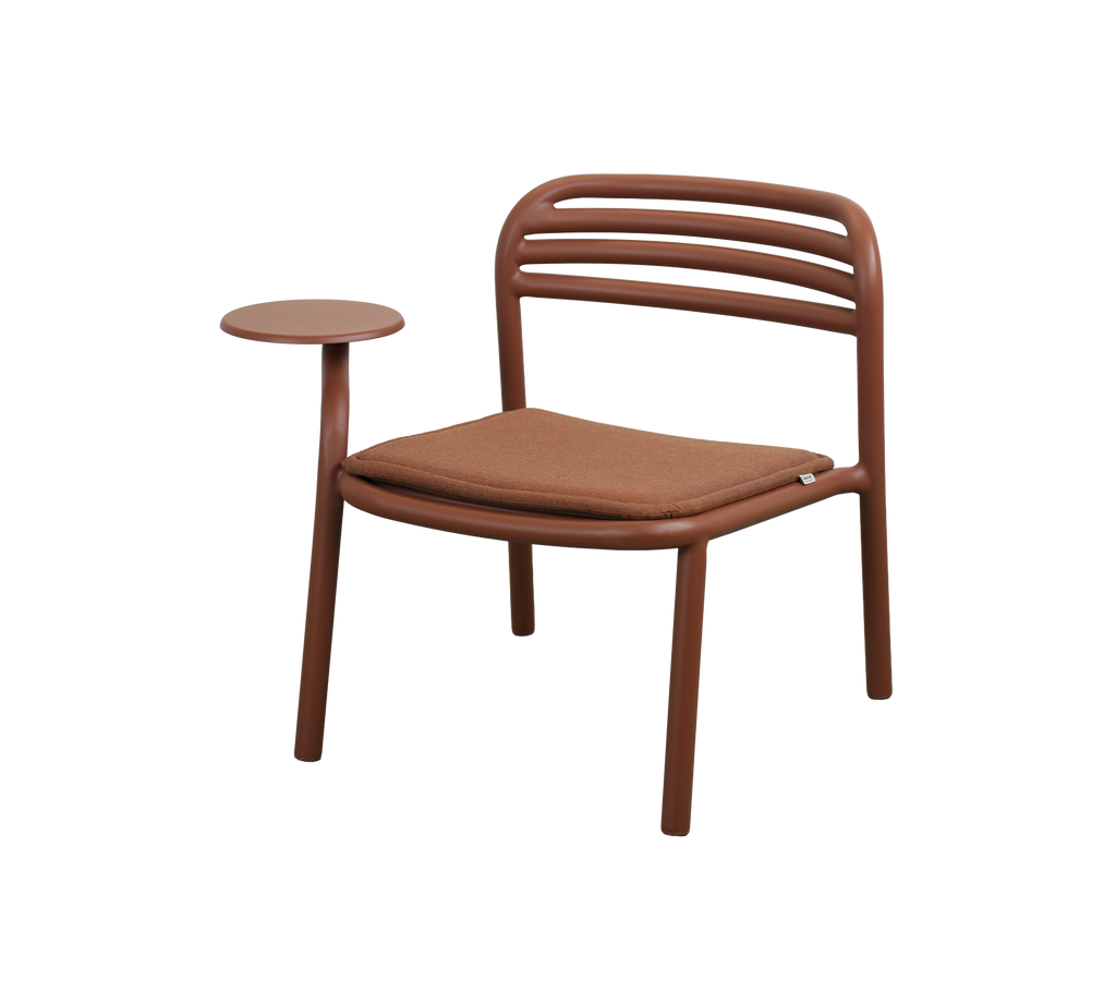 Modern stol i ökenröd med ett litet sidobord.