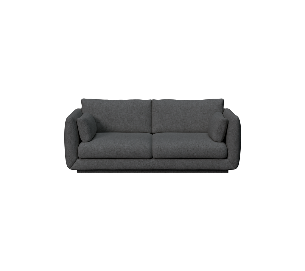 Modern mörkgrön soffa med kuddar.