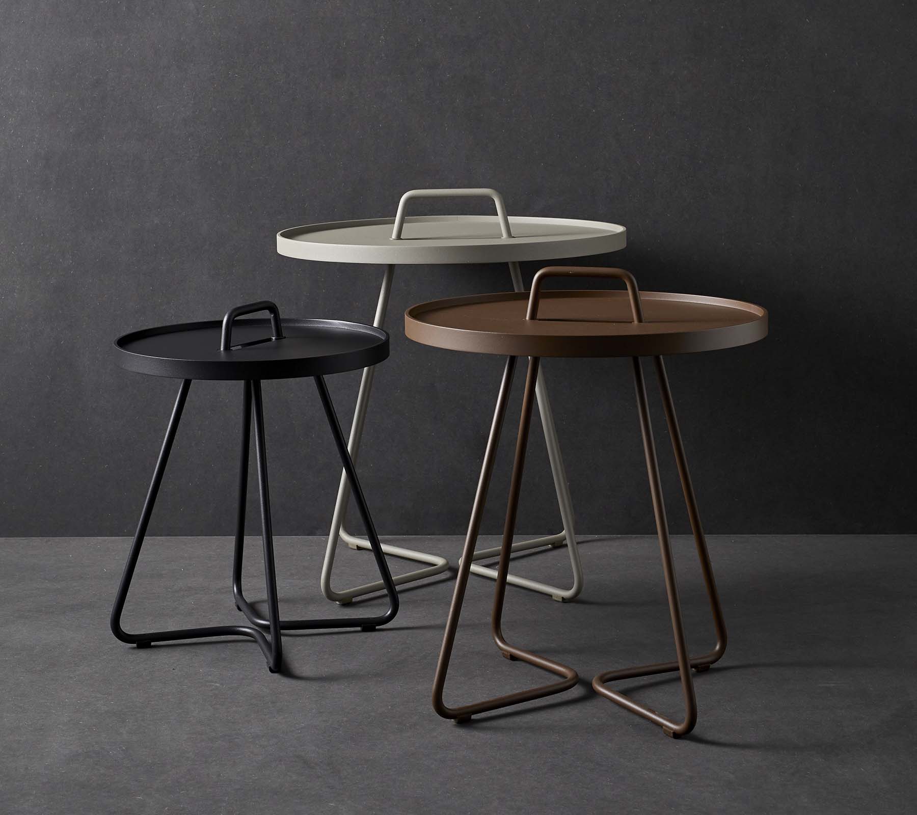 Tre stiliga sidobord med runda toppar och unika handtagsdesigner, som har en blandning av färger inklusive svart, vitt och brunt.