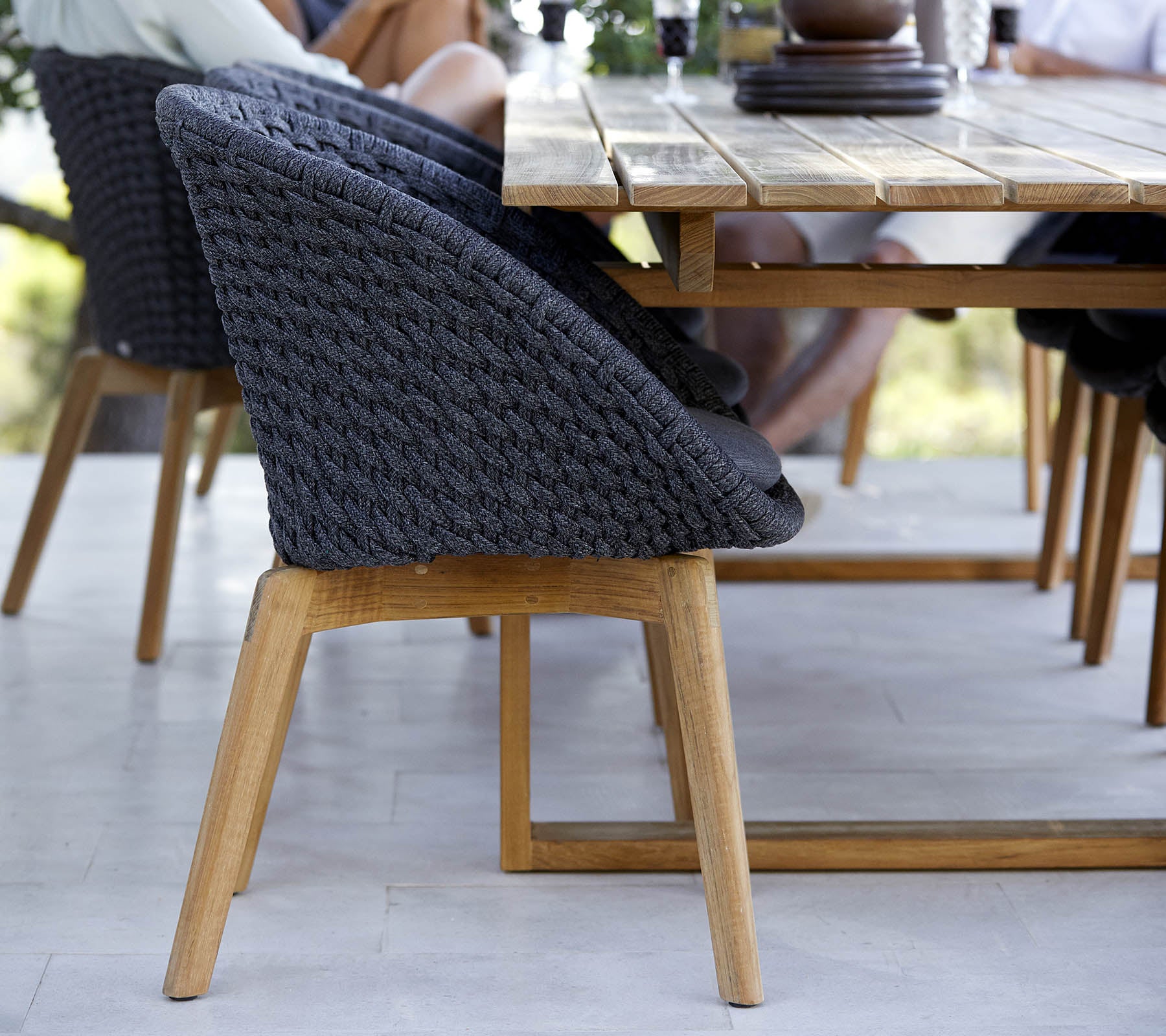 Stilfullt vävd stol med en träbas, placerad bredvid ett bord, som visar en modern design perfekt för samlingsutrymmen.