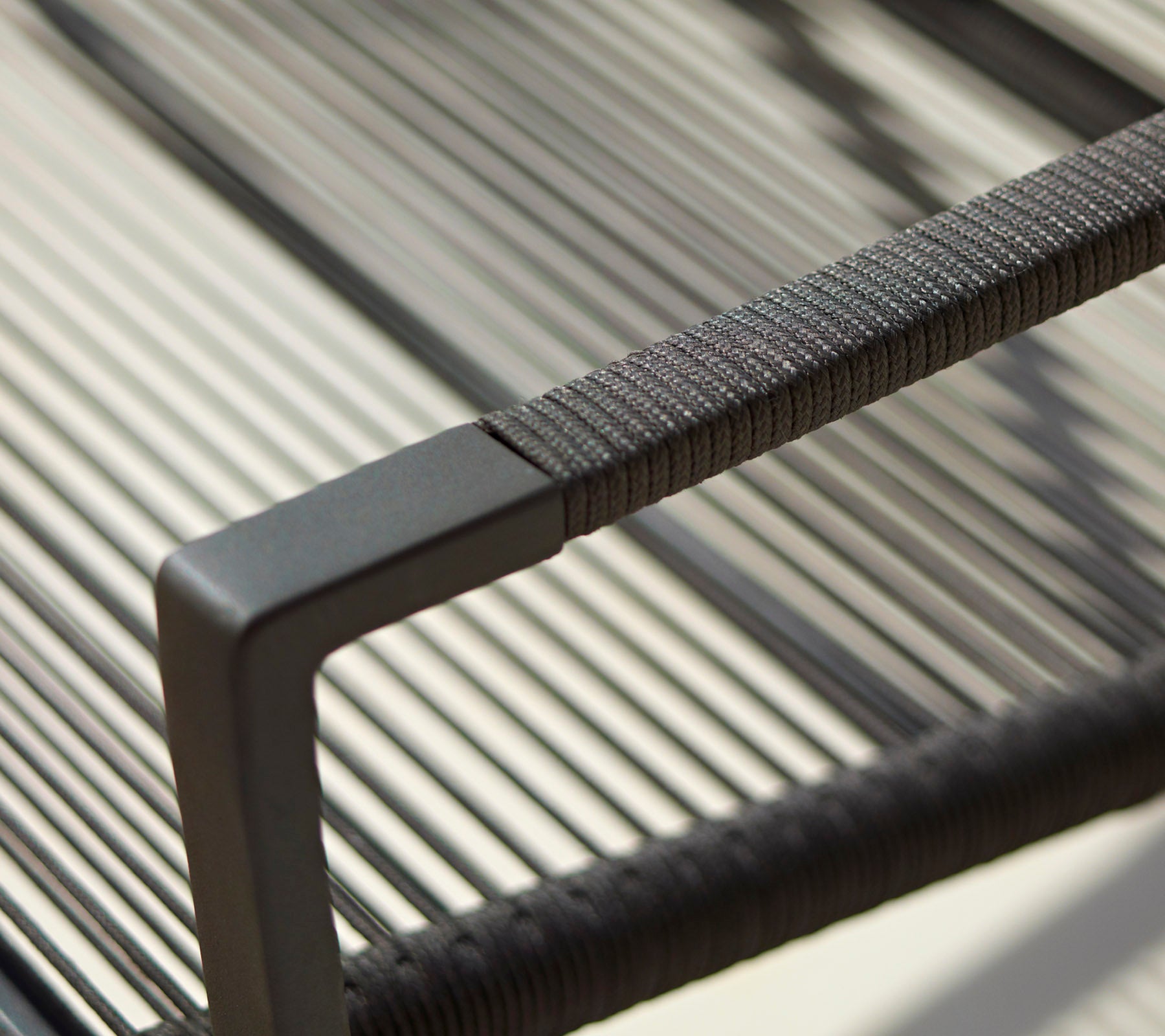 Närbild av en modern stolsarmstöd med en slank design, texturerade detaljer och en minimalistisk svart finish.