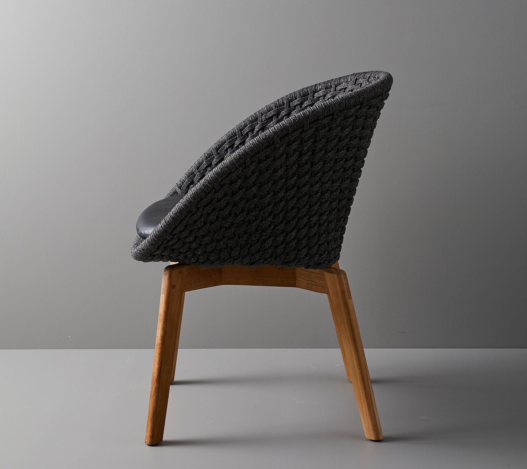 Stilren stol med vävd ryggstöd och ben av trä, som erbjuder en modern design som är idealisk för samtida utrymmen.