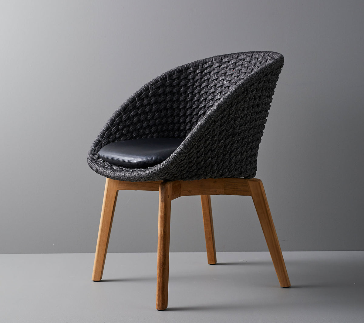 Stilfull vävd stol med en bekväm dyna, med släta, avsmalnande träben och en modern design som passar i olika miljöer.