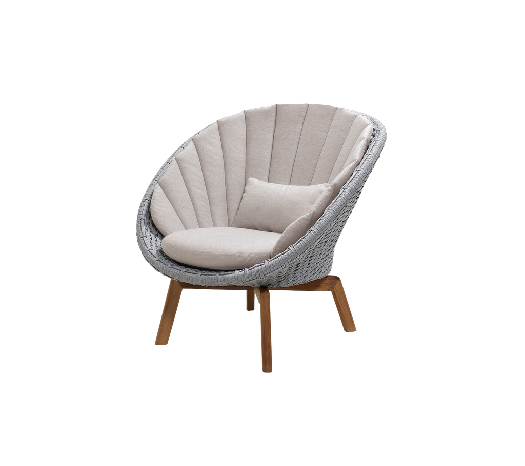 Modern ljusgrå stol med sandkudde i en loungeinställning.