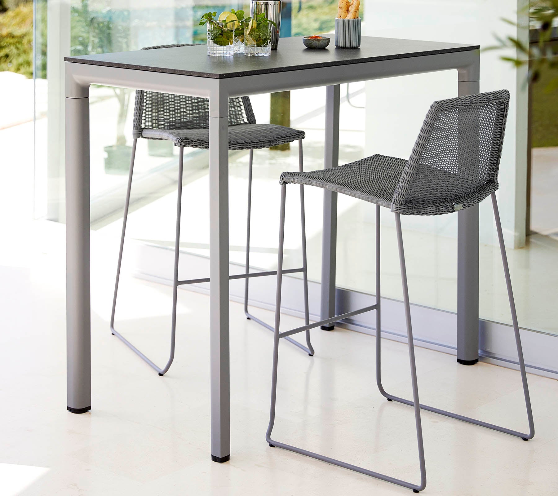 Ett stilrent bord med två höga barstolar, med en modern design och ljus färgsättning, komplett med en liten växt som mittpunkt.