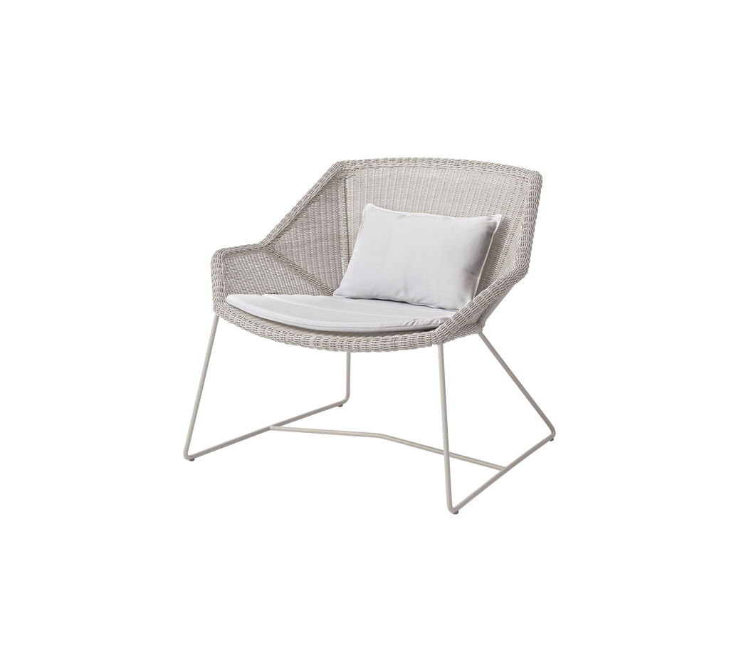 Modern vit stol med en vit kudde i en loungemiljö.