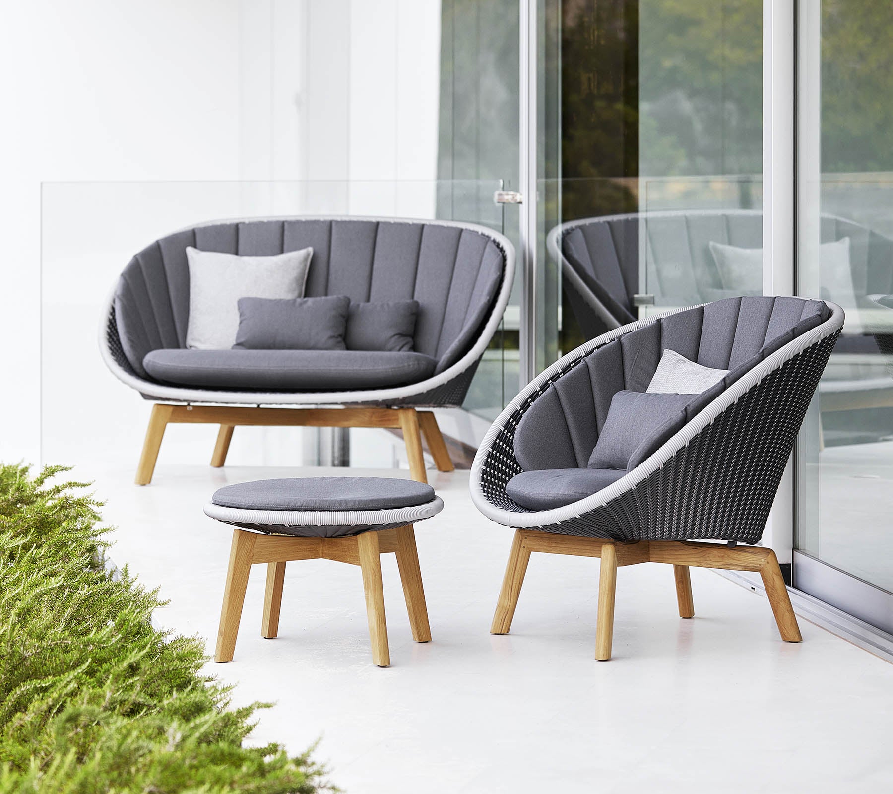 Stiligt sittset med en böjd soffa, stol och runt kaffebord, alla med modern design och mjuka grå kuddar.