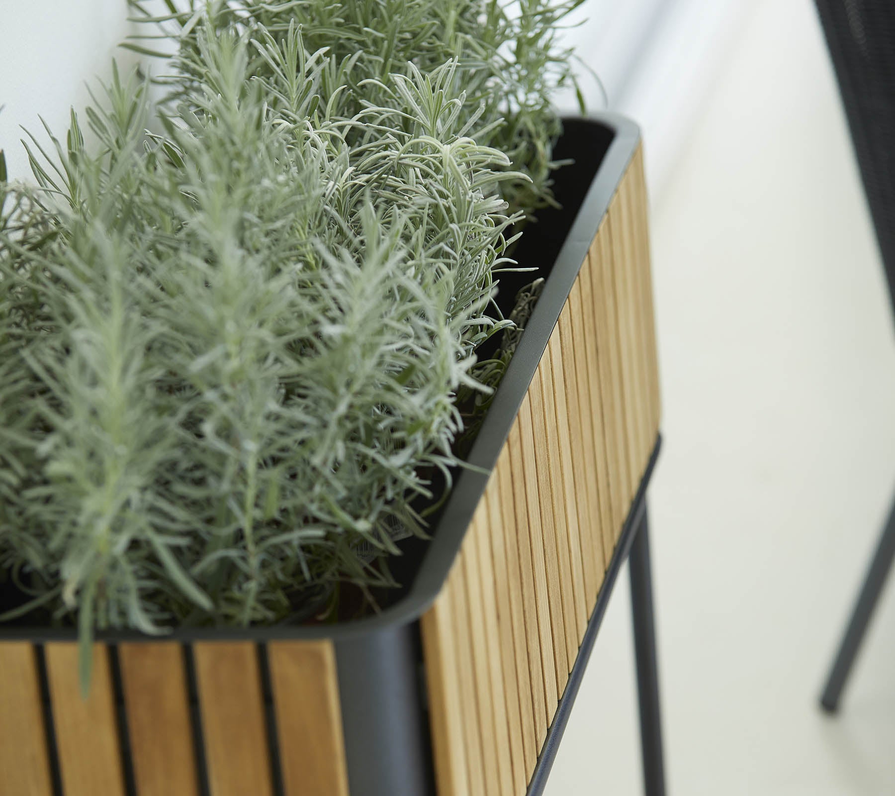 Planter med en slank design som har en yttre av träslister och frodiga gröna växter, vilket ger en känsla av natur till omgivningen.
