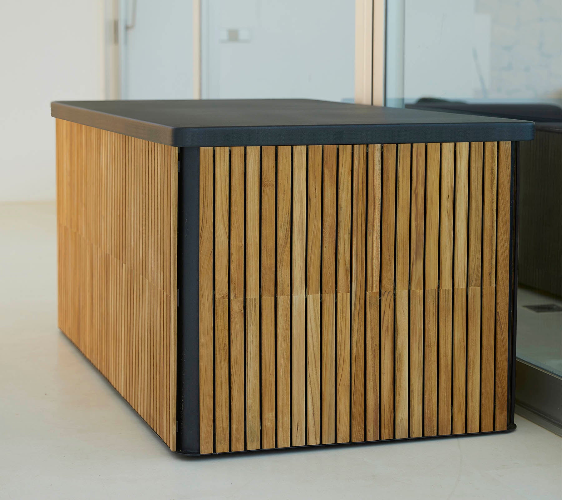Ett modernt träbord med vertikala spjälor på sidorna och en stilren mörk yta som erbjuder en stilfull och funktionell design.