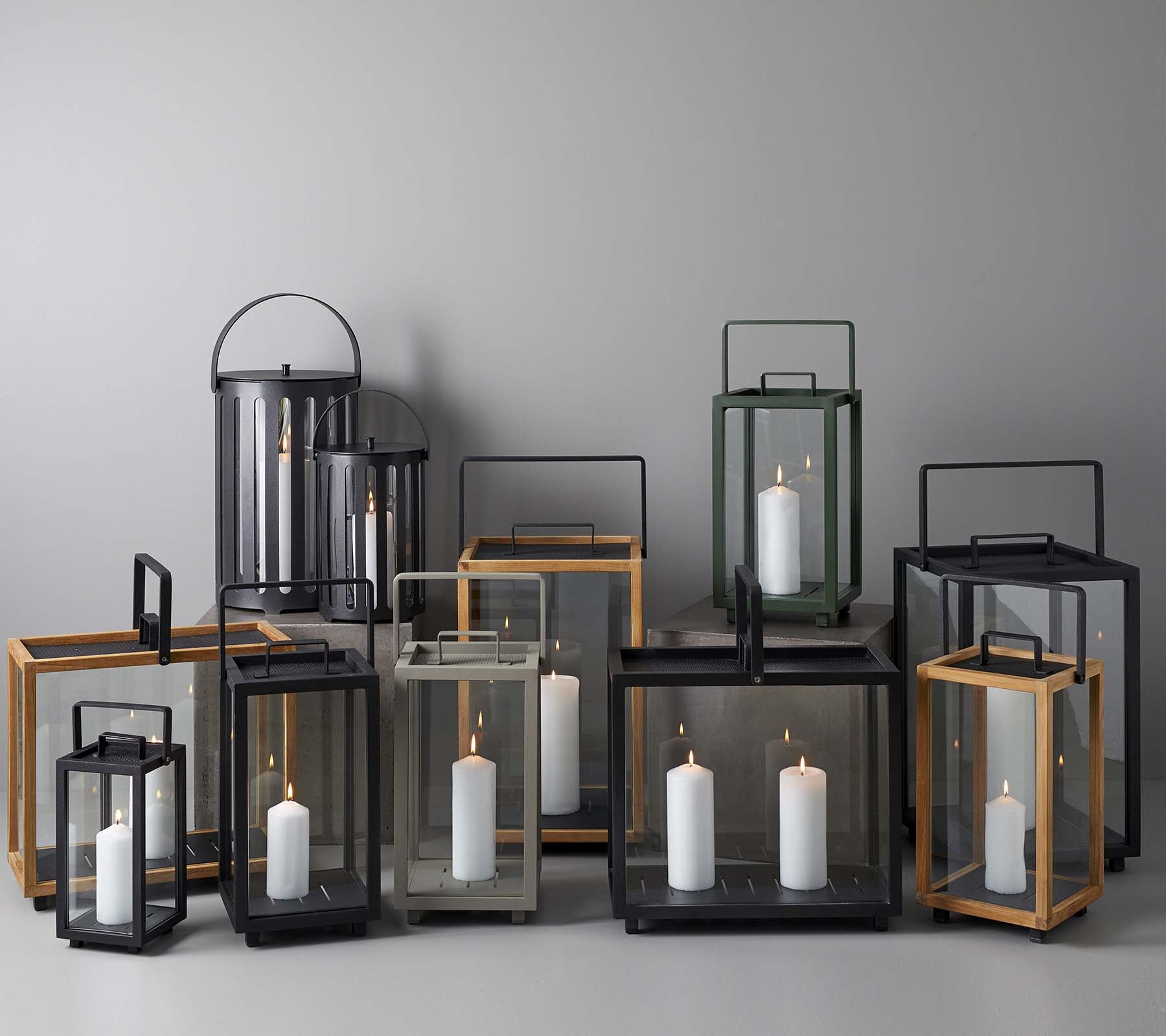 En samling av eleganta lyktor i olika storlekar och stilar, med ljus inuti, arrangerade tillsammans på en neutral bakgrund.