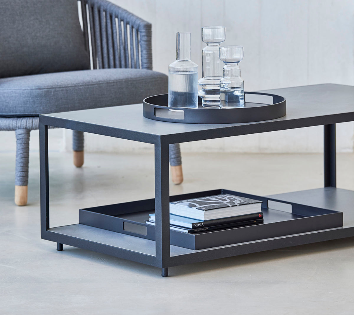 Modernt soffbord med en sleek design, med en bricka, glas och böcker på den nedre hyllan. Perfekt för stiliga vardagsrum.