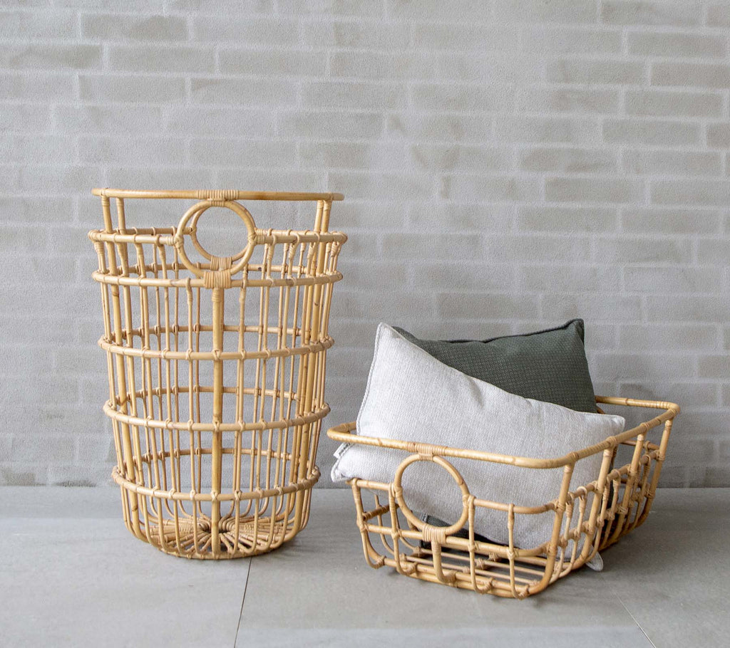 Moderna vävda korgar med grå och gröna kuddar i en minimalistisk miljö.