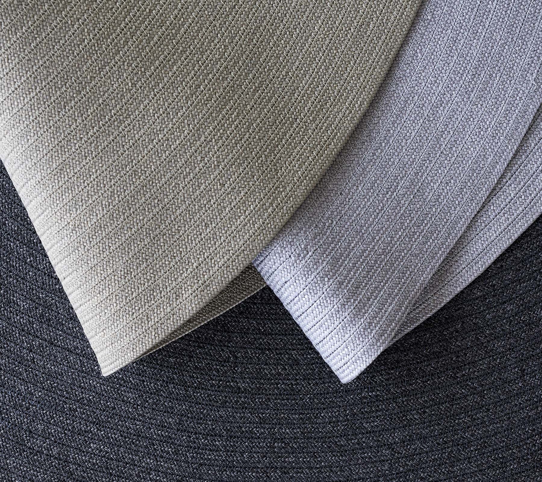 Tre överlappande texturerade tyger i olika grå nyanser, som visar olika mönster och toner för designapplikationer.
