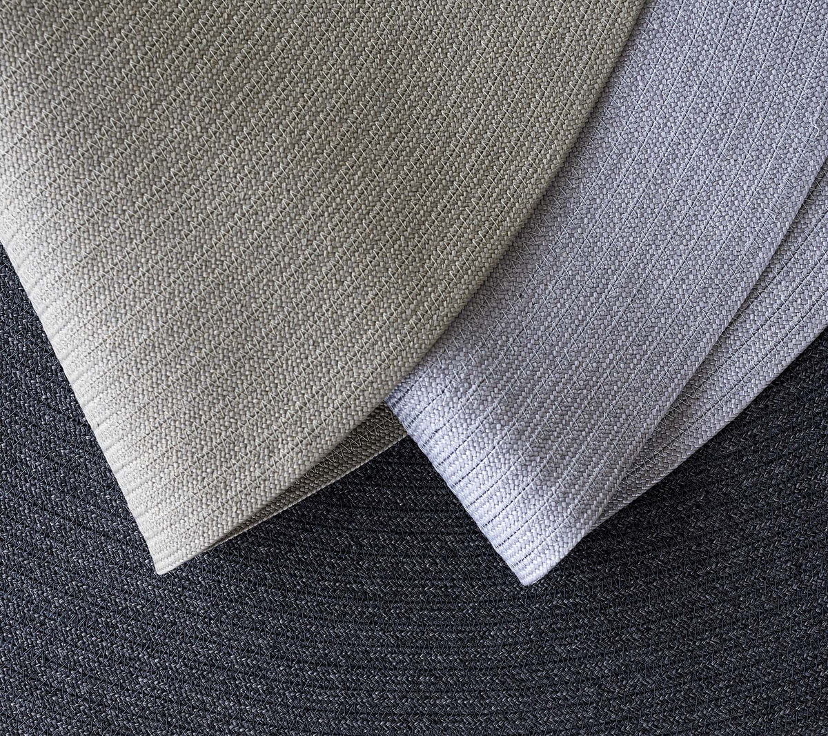 Tre överlappande texturerade tyger i olika grå nyanser, som visar olika mönster och toner för designapplikationer.